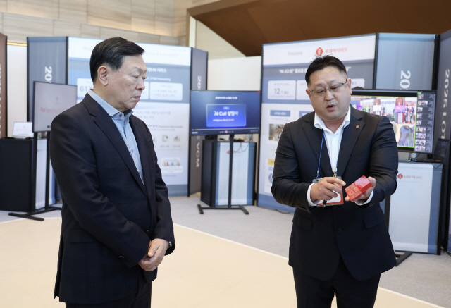 신동빈(왼쪽) 롯데그룹 회장이 9일 서울 잠실 롯데월드타워에서 열린 '상반기 VCM' 행사 참석에 앞서 계열사들이 전시한 인공지능(AI) 우수 혁신사례에 대한 설명을 듣고 있다. 롯데지주 제공